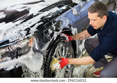Man worker washing car\'s alloy wheels on a car wash