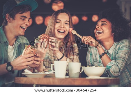 Cheerful multiracial friends eating in a cafe