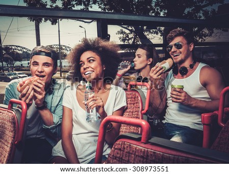 Multinational friends having snack while riding on a sightseeing bus