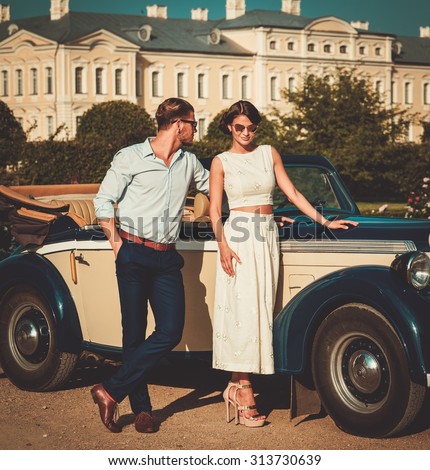 Wealthy couple near classic convertible against royal palace