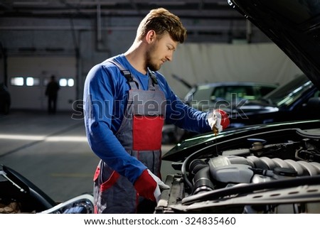 Mechanic checking oil level in a car workshop