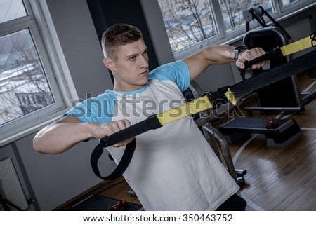 Attractive man during workout with suspension straps In The Gym's Studio