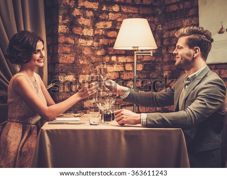Stylish wealthy couple toasting with champagne in a restaurant.