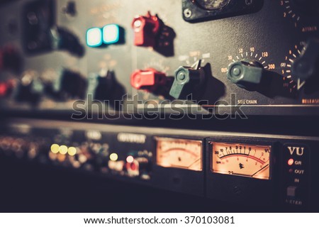 Close-up amplifier equipment with sliders and knobs at boutique recording studio.