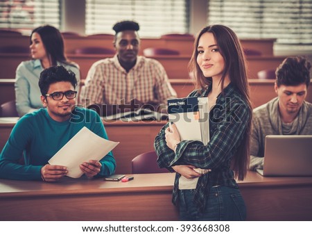 Multinational group of cheerful students taking an active part in a lesson while sitting in a lecture hall.