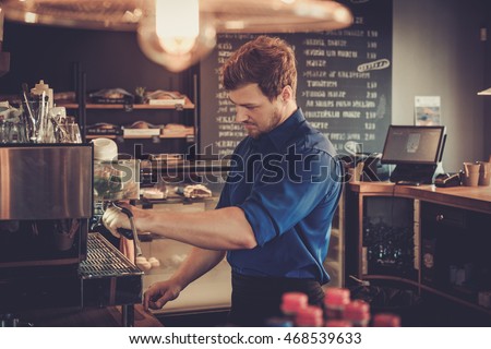 Handsome barista preparing cup of coffee for customer in coffee shop.