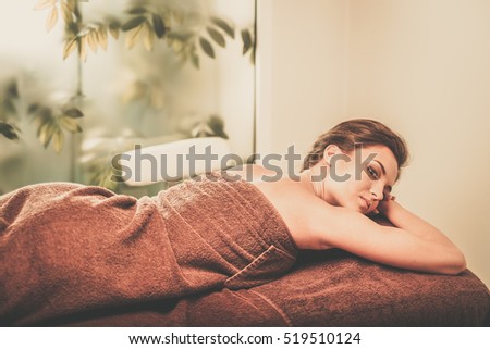 Beautiful young woman having massage in a spa salon.