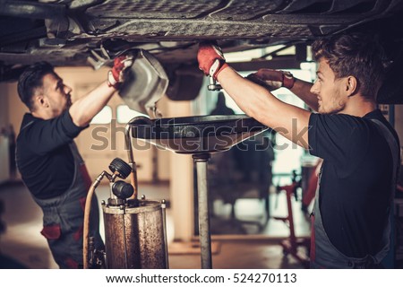 Profecional car  mechanic changing motor oil in automobile engine at maintenance repair service station in a car workshop.