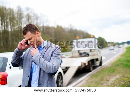 Man calling while tow truck picking up his broken car.