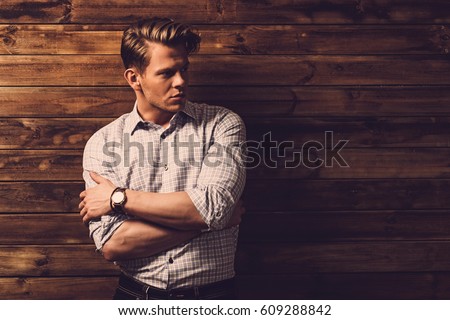 Handsome man wearing checkered shirt in wooden rural house interior