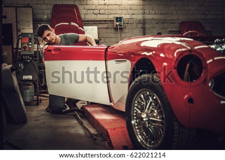 Mechanic working on car body details in restoration workshop