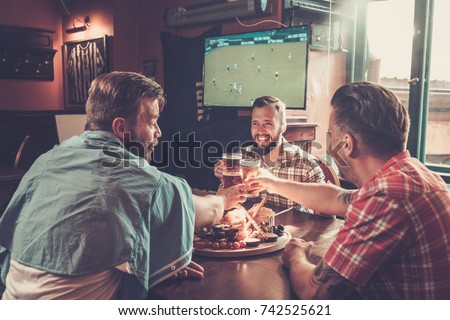 Friends drinking beer and watching soccer in a pub