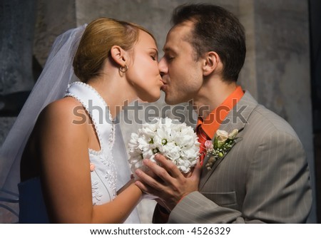 Just married couple kissing holding a round bouquet of white flowers