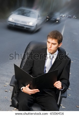 Handsome business man on sitting in executive chair on a road