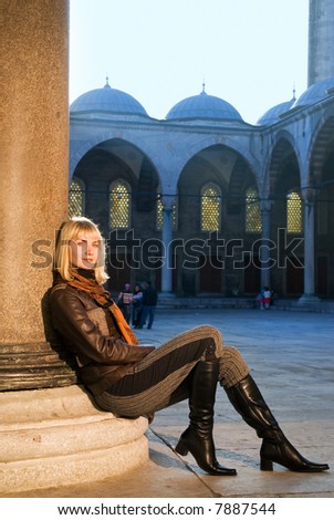 Beautiful blond girl sitting near the column