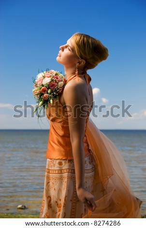 Lovely redhead lady with a bouquet of flowers near the sea