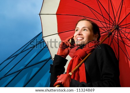 Beautiful brunette with red umbrella talking on the phone