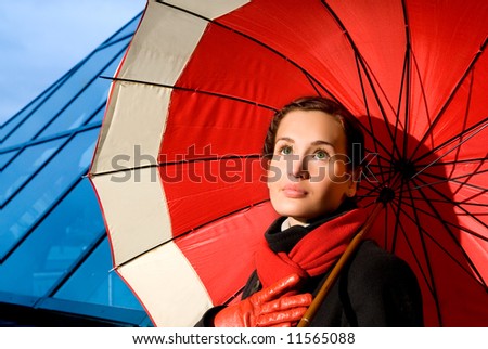 Beautiful young woman with red umbrella on rainy day