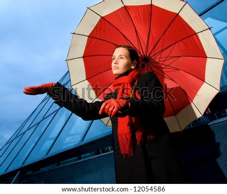 Beautiful young woman with red umbrella on rainy day