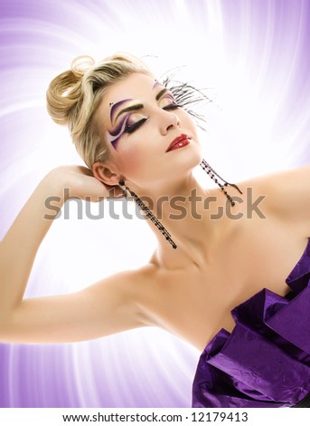 Beautiful young woman with artistic make-up over abstract purple background