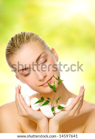 Beautiful young woman holding plant growing up through stones