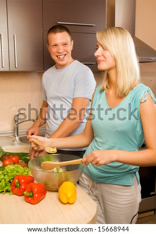 Young couple making vegetable salad in the kitchen