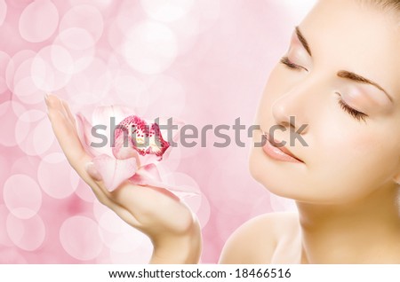 stock photo Beautiful young woman with pink orchid over abstract blurred 
