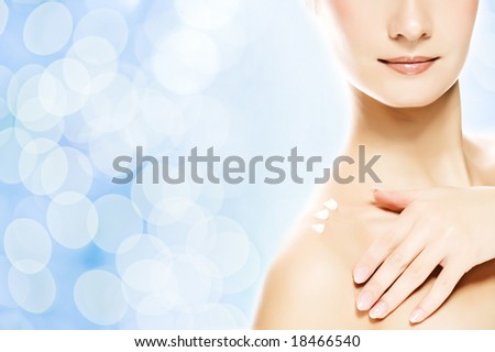 Young beautiful woman applying moisturizer to her skin after shower