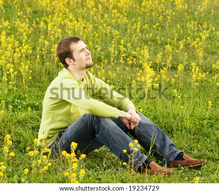 Relaxed young man sitting in a flower field