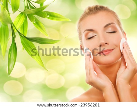 Beautiful young woman removing cosmetics with cleansing pad