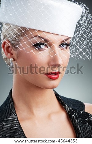 Beautiful young woman in white hat with net veil. Retro portrait