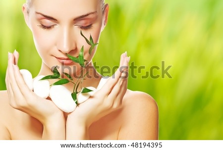 Beautiful young woman holding plant growing up through stones