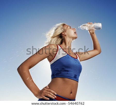 Young woman drinking water after fitness exercise