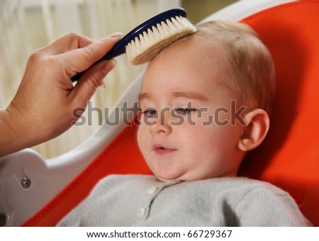 Mother combing her baby\'s hair