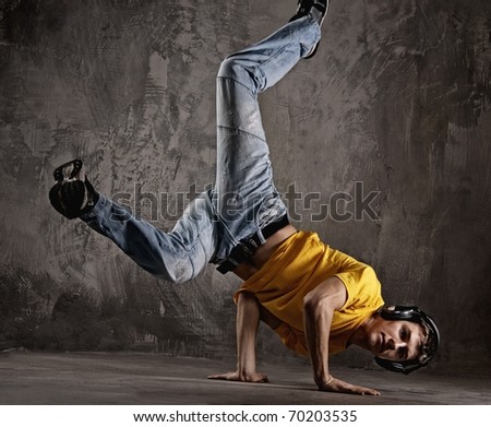 Young man dancing against grunge wall