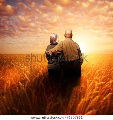 Senior couple standing in a wheat field at sunset Senior couple standing in a wheat field at sunset