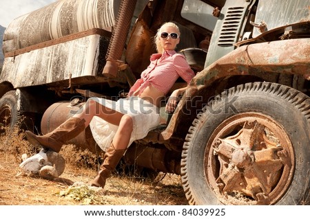 Attractive blond woman near an old truck.
