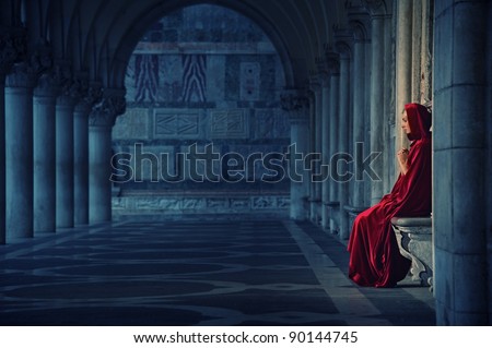 Woman in red cloak praying alone