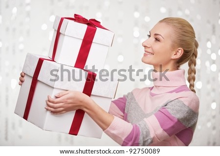 Smiling woman in cashmere sweater with gift boxes.