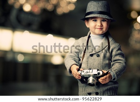 Baby boy with retro camera over blurred background.