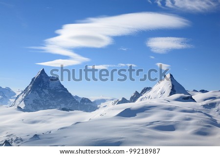 Dramatic mountain summits with snow, blue sky and cloud patterns