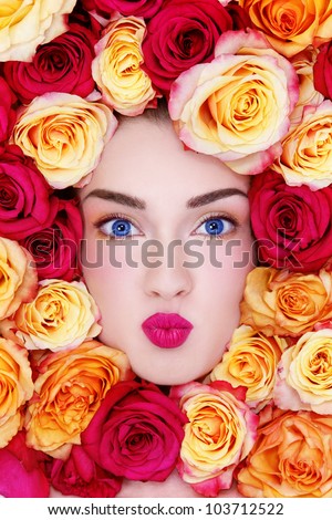 Portrait of young beautiful blue-eyed woman with funny expression and colorful roses around her face