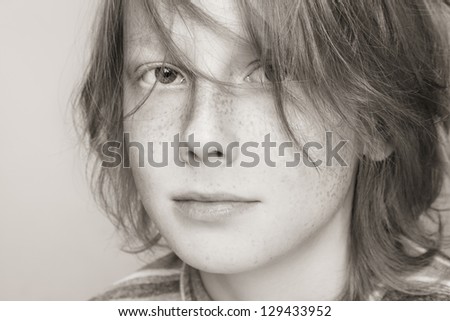 Close-up duotone portrait of freckled teen boy