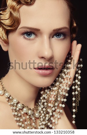 Portrait of beautiful young woman with retro hairstyle and fancy necklace