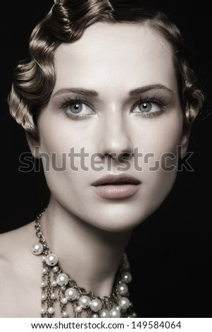 Portrait of beautiful young woman with retro hairstyle and fancy necklace