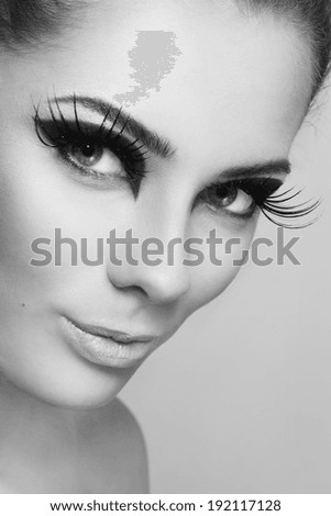 Close-up black and white portrait of young beautiful woman with stylish make-up and huge false eyelashes