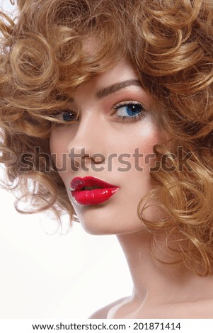 Portrait of young beautiful blue-eyed woman with curly hair and red lipstick