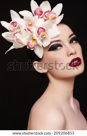 Young beautiful woman with fancy make-up and white orchids in her hair