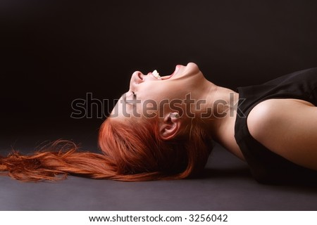 Red-haired woman laying on her back on the floor and laughing like mad