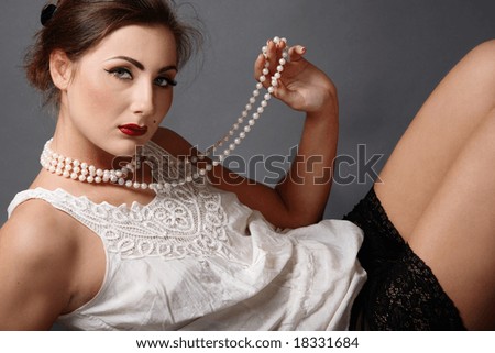 Beautiful girl in white vintage blouse and black lacy panties holding necklace of pearl beads